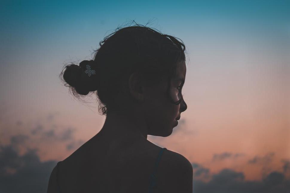 A silhouette of a girl against a sunset sky.